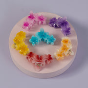 Colorful flower-shaped hair clips arranged in a circular pattern on a white base.