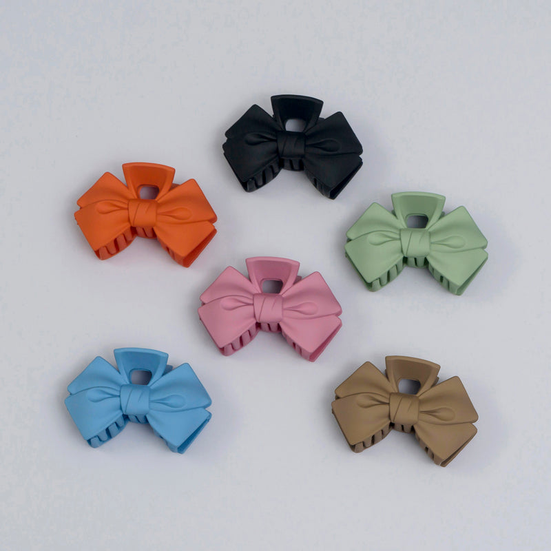 Set of colorful bow-shaped hair clips on a light gray background