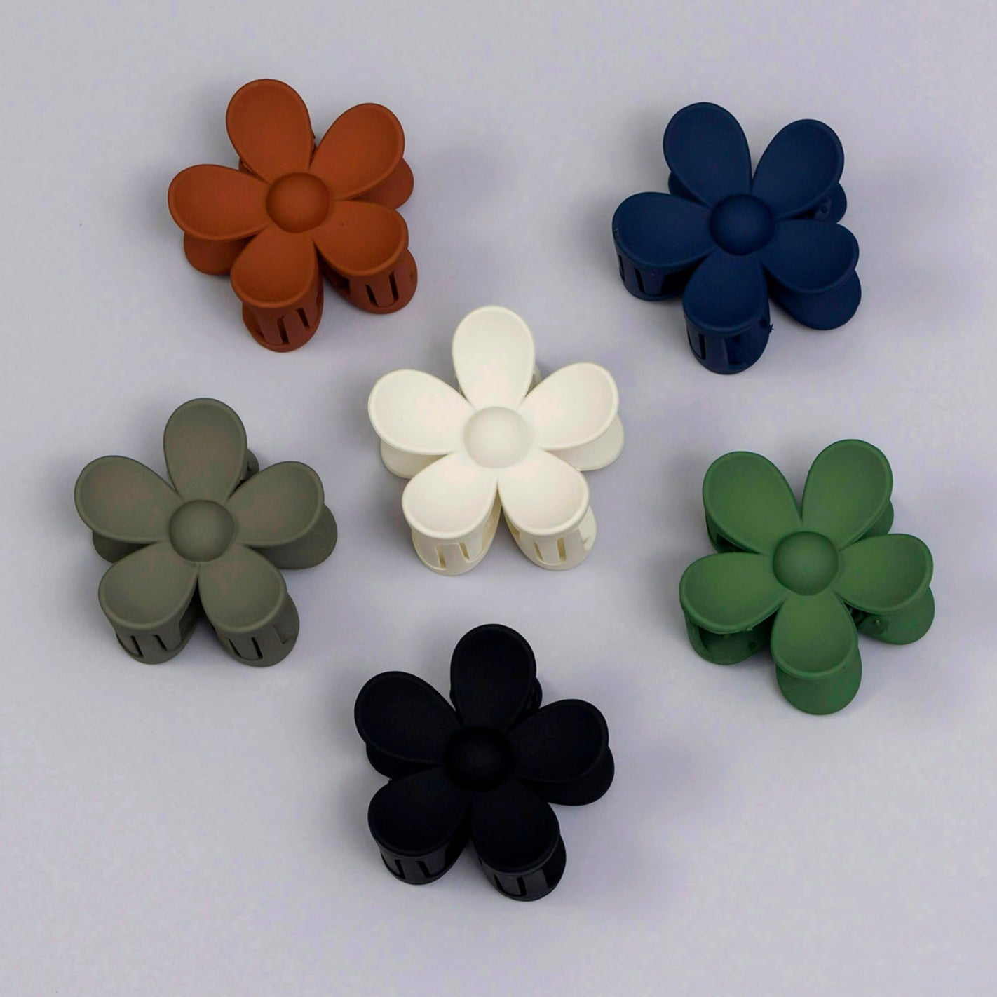 Set of six flower-shaped objects in different colors on a light gray background