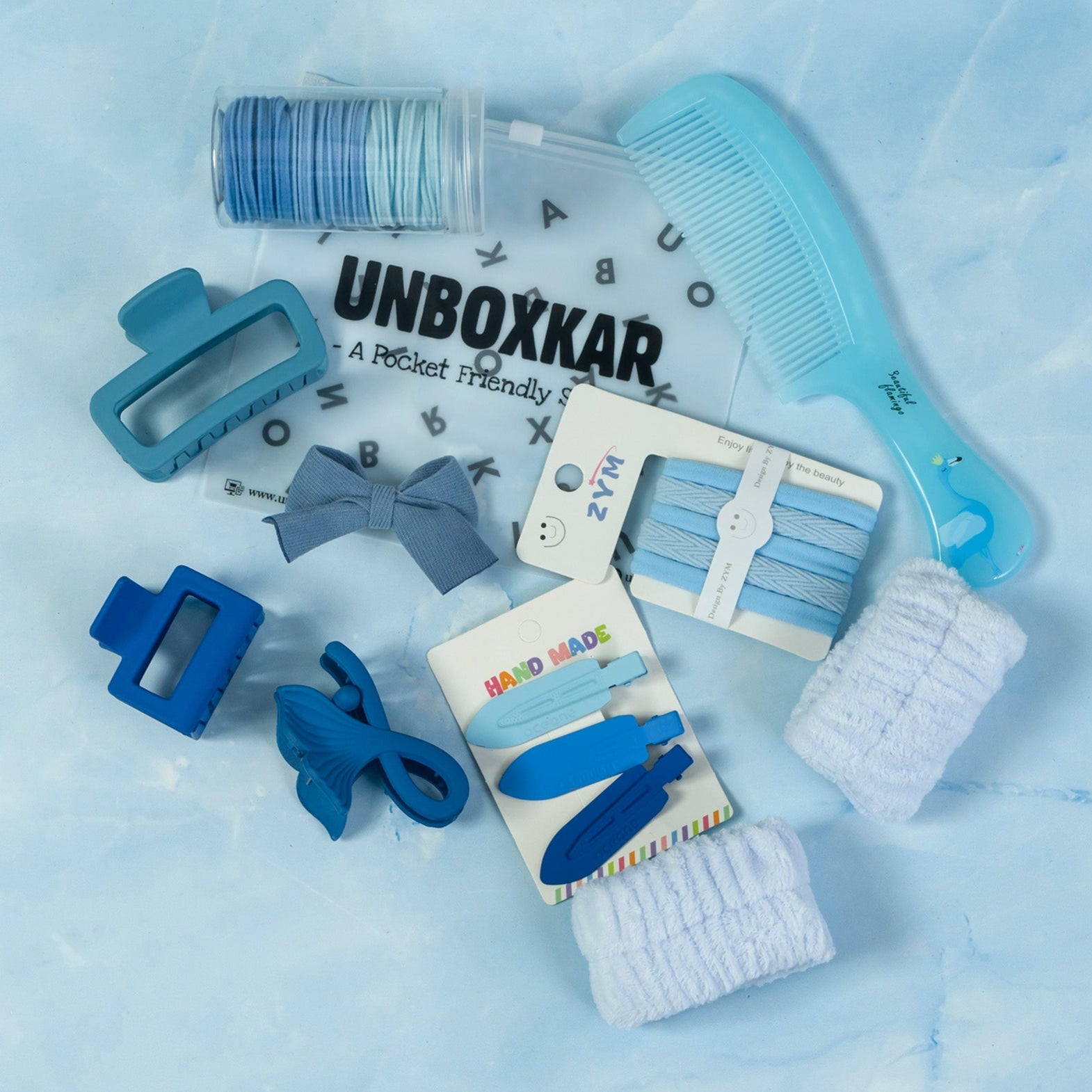 Collection of blue hair accessories and tools on a light blue background with 'Unboxkar' branding.