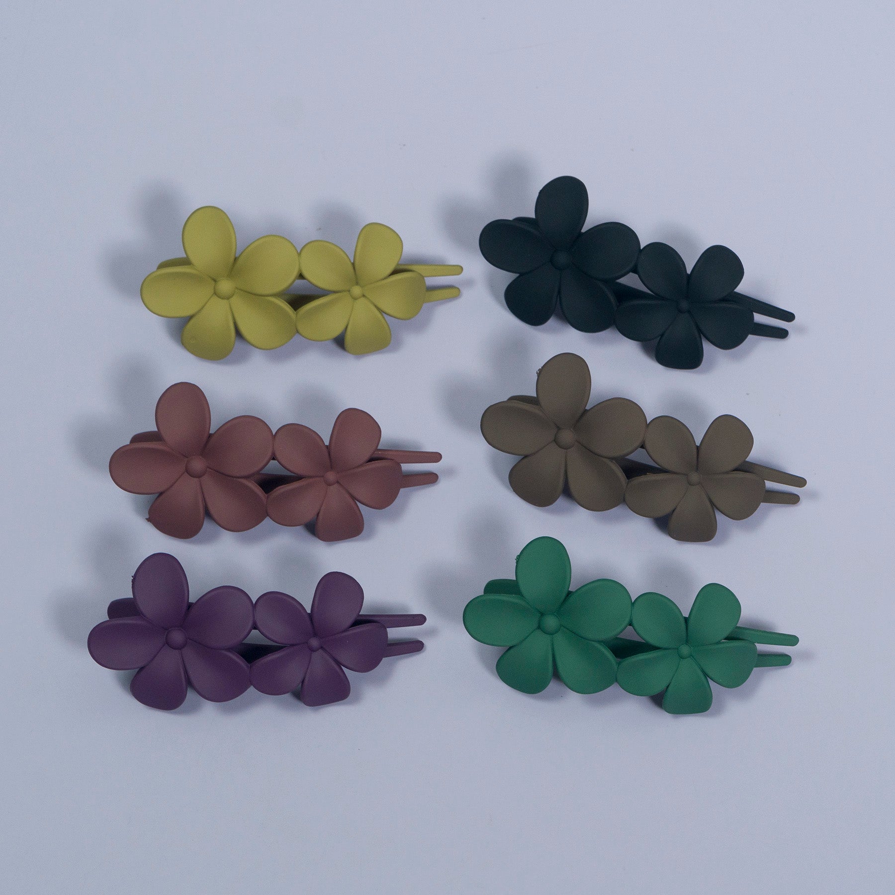 Set of six floral hair clips in different colors on a light gray background